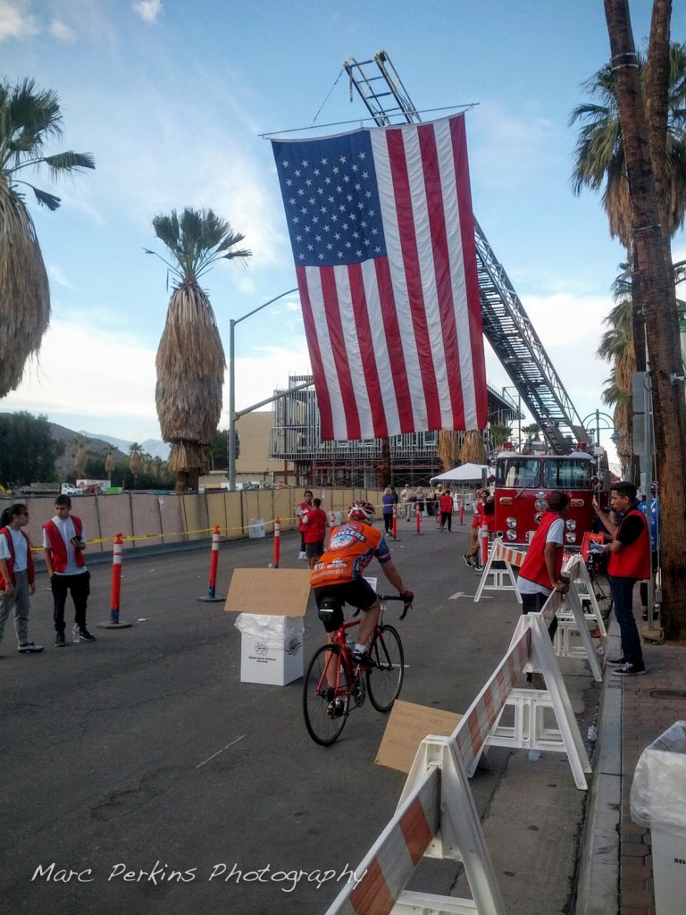 A giant flag hangs from a vintage fire truck at the finish line to the Tour de Palms 2016.