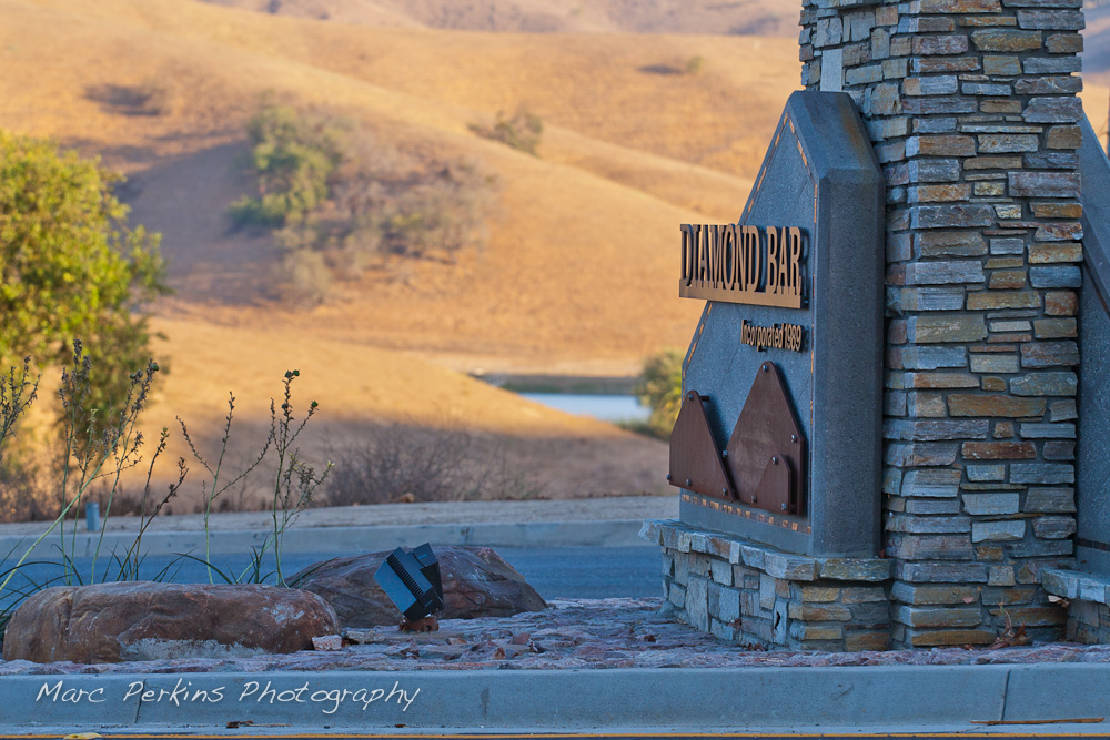 Hills and a pond are lit up by the setting sun, framing the already-shaded "Diamond Bar: Incorporated 1969" sign. This was part of the 2015 reconstruction of the Grand Avenue and Longview Drive intersection for Diamond Bar's 2015 "Grand Avenue Beautification" project; landscape architecture for the project was by David Volz Design.