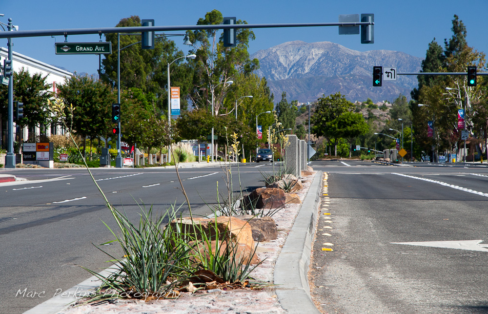 Mt. Baldy (Mount San Antonio) seen from the southern side of the Diamond Bar Boulevard and Grand Avenue intersection in Diamond Bar. Rocks, median art, and flowering plants (yellow yuccas - Hesperaloe parviflora) are all visible, including a car. The stoplight is showing all green lights and a green left turn signal. This was part of the 2015 rebuild of the Grand Avenue and Diamond Bar Boulevard intersection for Diamond Bar's 2015 "Grand Avenue Beautification" project, landscape architecture for the project was by David Volz Design.
