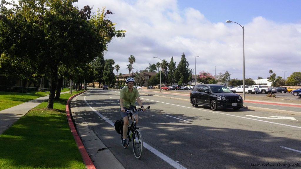 Cyclist in a bike lane with a car near her.