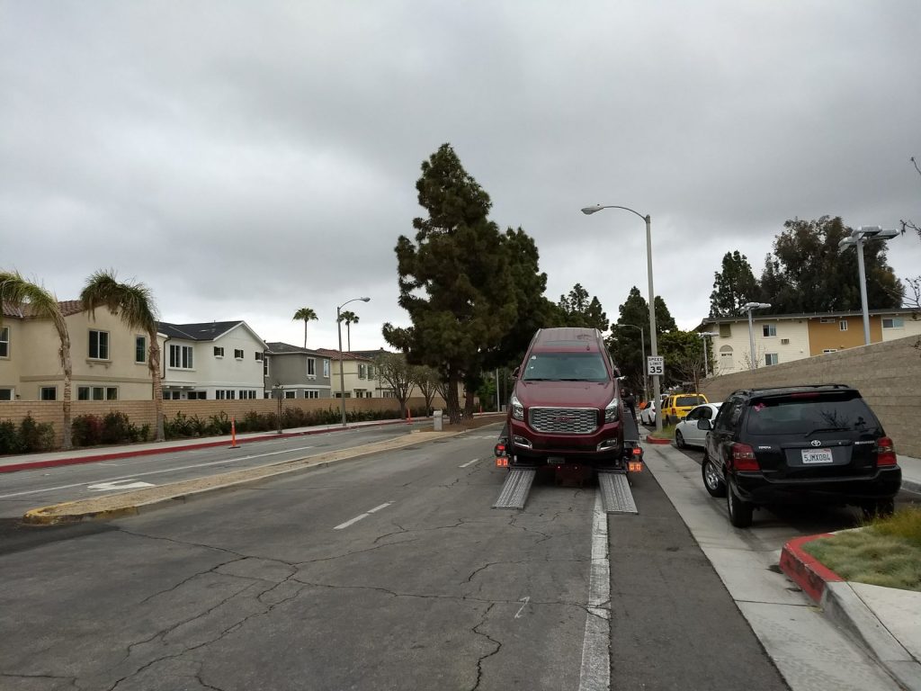 A car carrier is parked in the bike lane and right-hand lane of traffic unloading vehicles during the Merrimac Way demonstration.