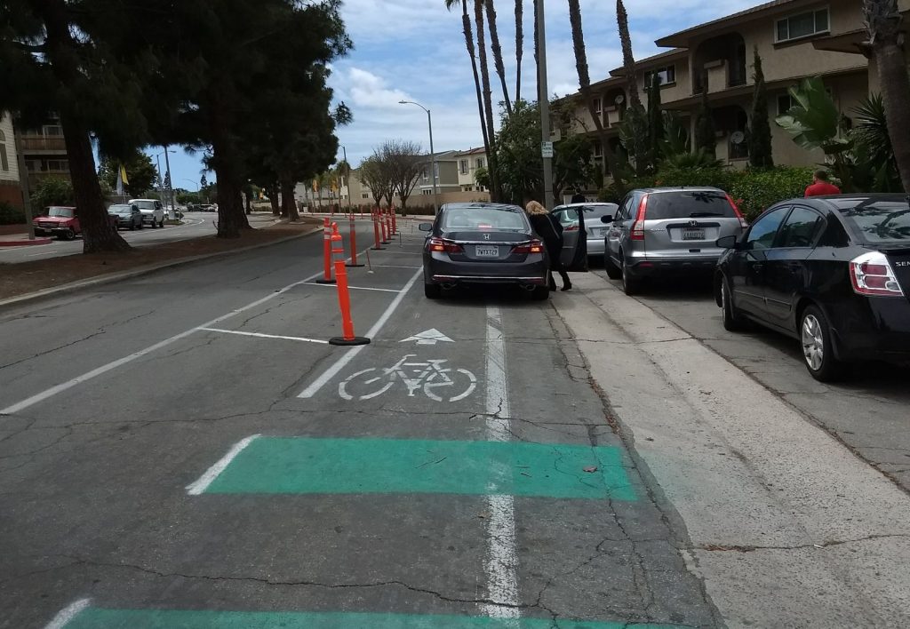 A car is parked in the demonstration protected bike lane along Merrimac Way.